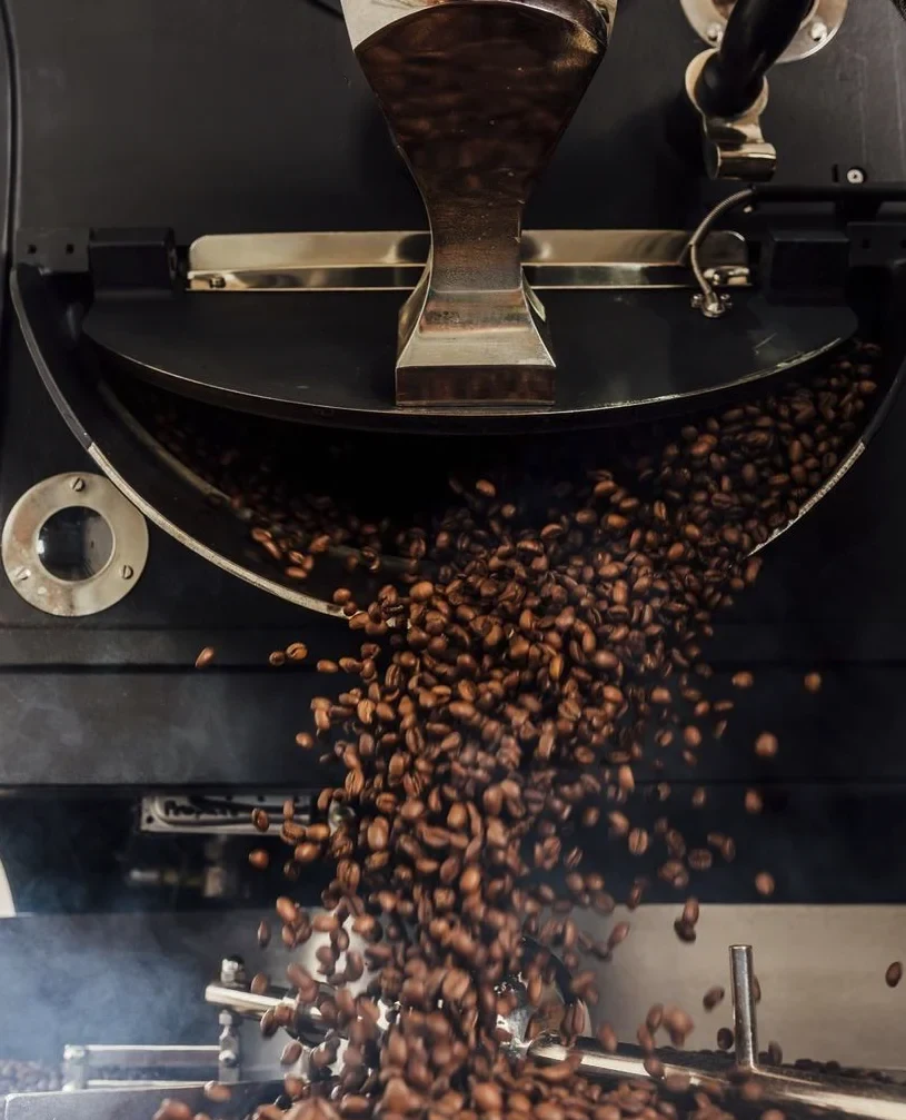 Freshly roasted coffee beans cascading from a commercial coffee roaster